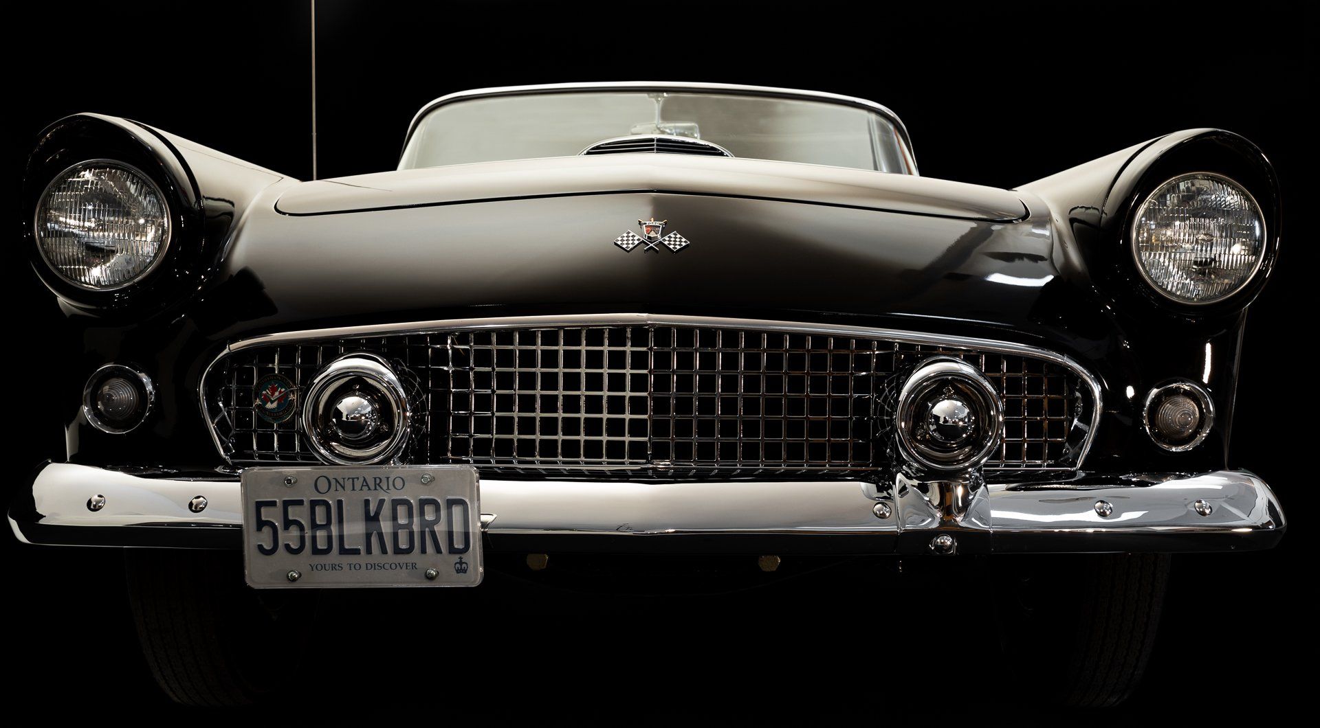 Black vintage 1955 Ford Thunderbird convertible with chrome detailing; Kansas license plate.