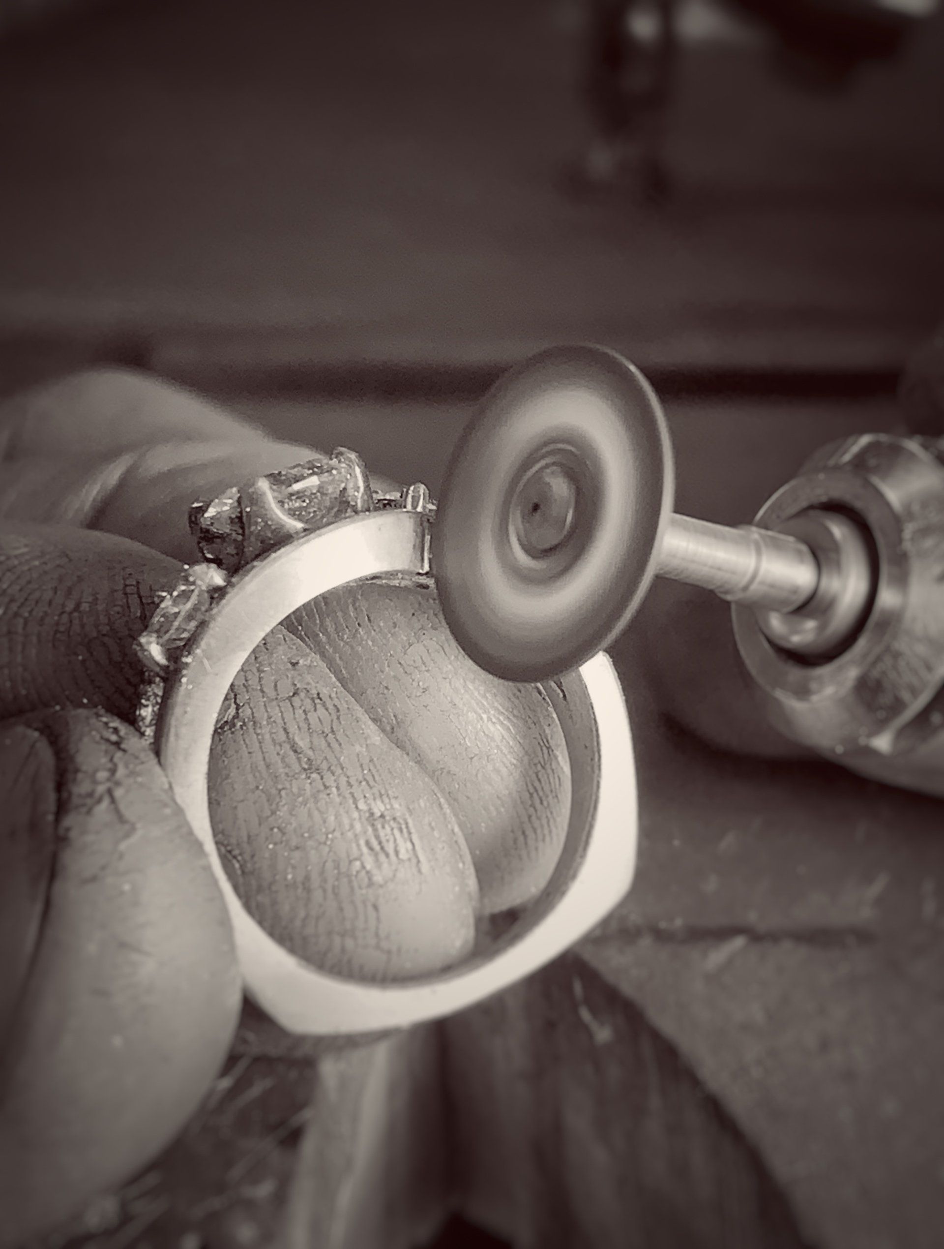A person is polishing a ring with a machine in a black and white photo.