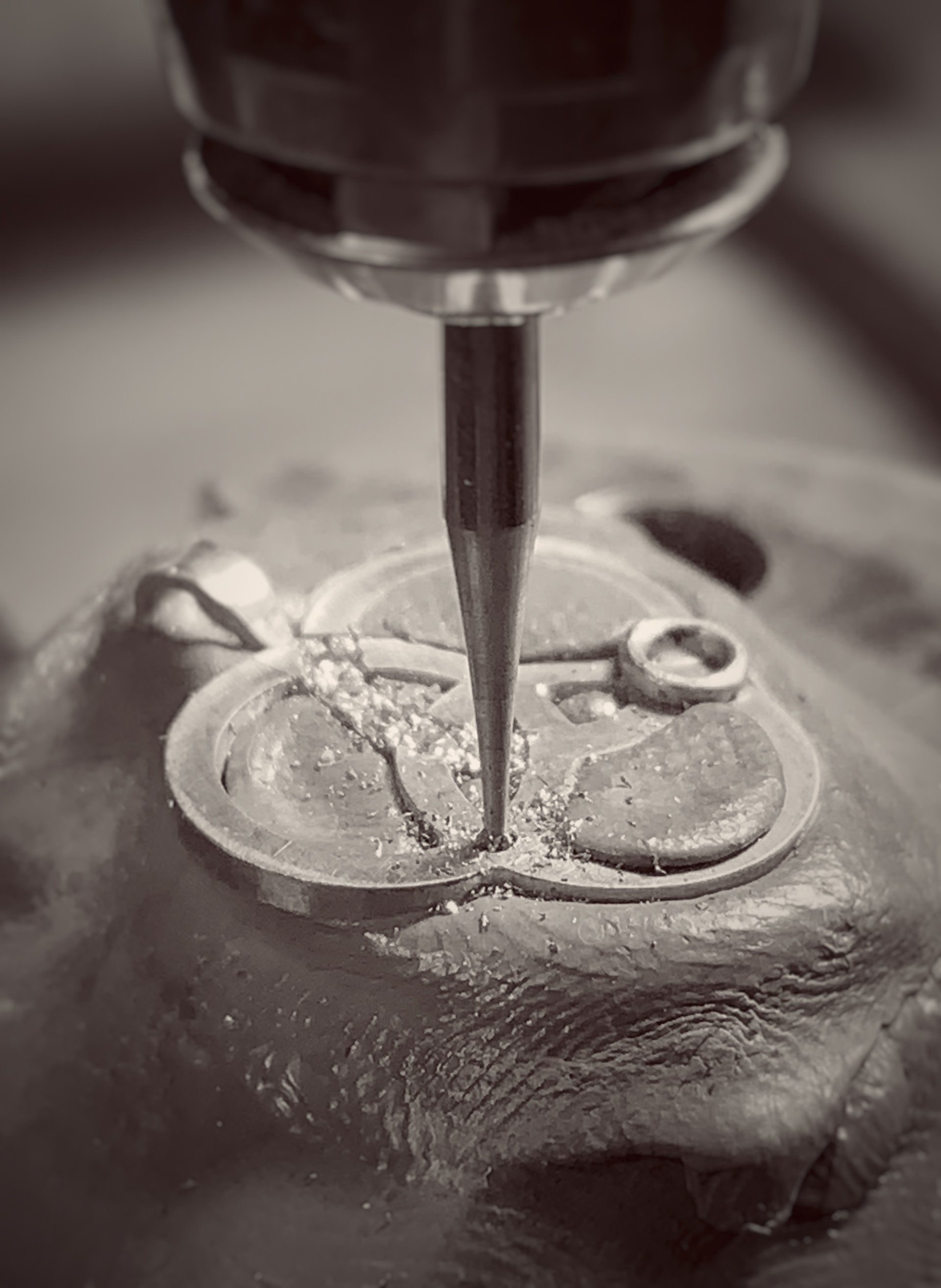 A black and white photo of a machine cutting a piece of metal.