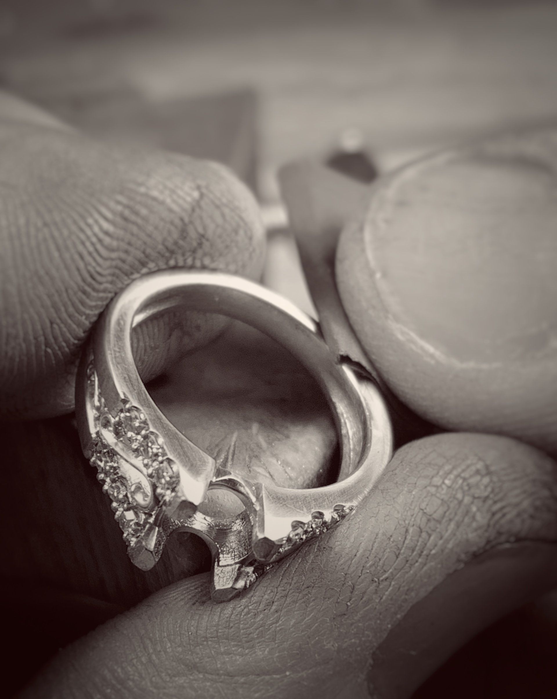 A person is holding a ring in their hand in a black and white photo.