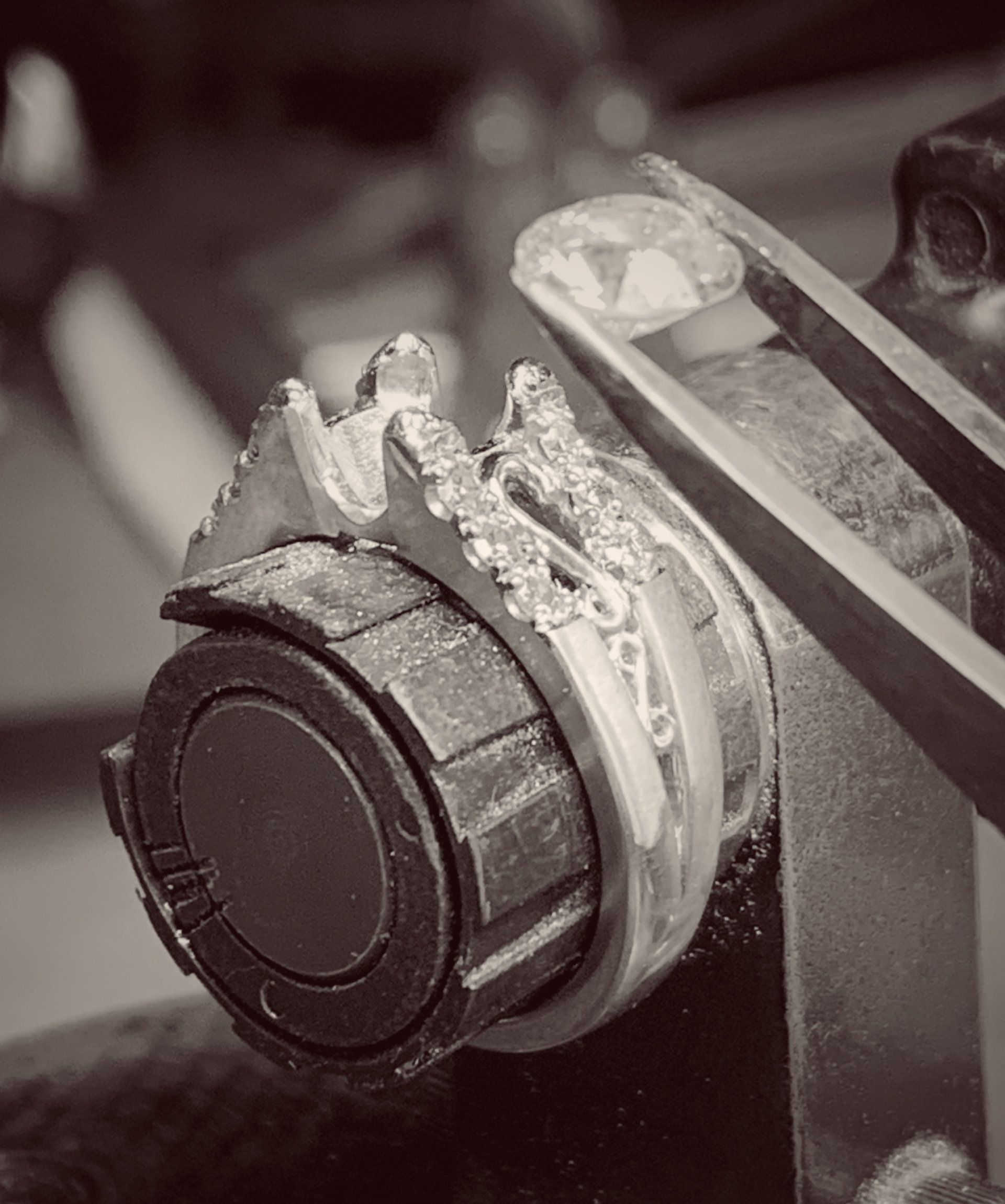 A black and white photo of a ring being worked on with tweezers.