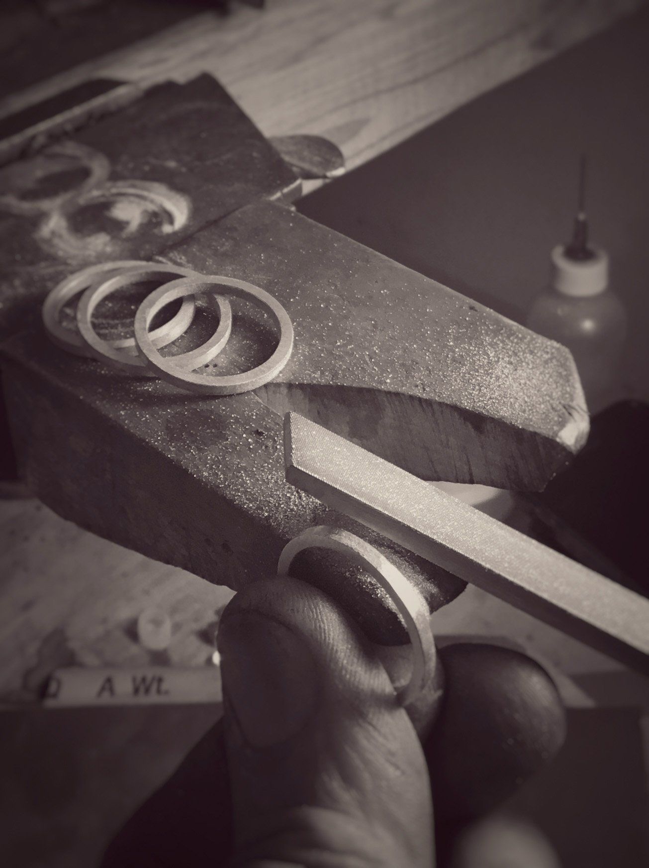 A black and white photo of a person cutting a piece of metal