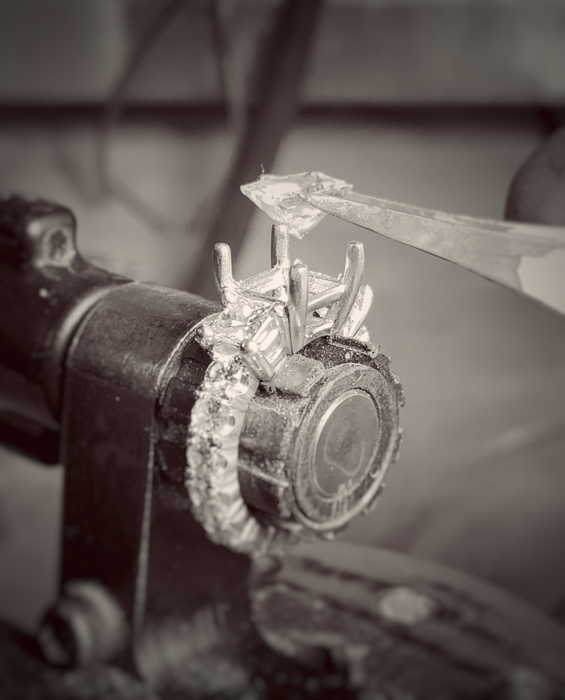 A black and white photo of a person working on a ring.