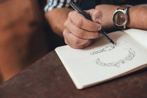 A man is writing in a notebook while wearing a watch.