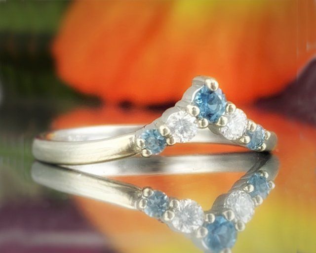 A silver ring with blue and white stones sits on a table