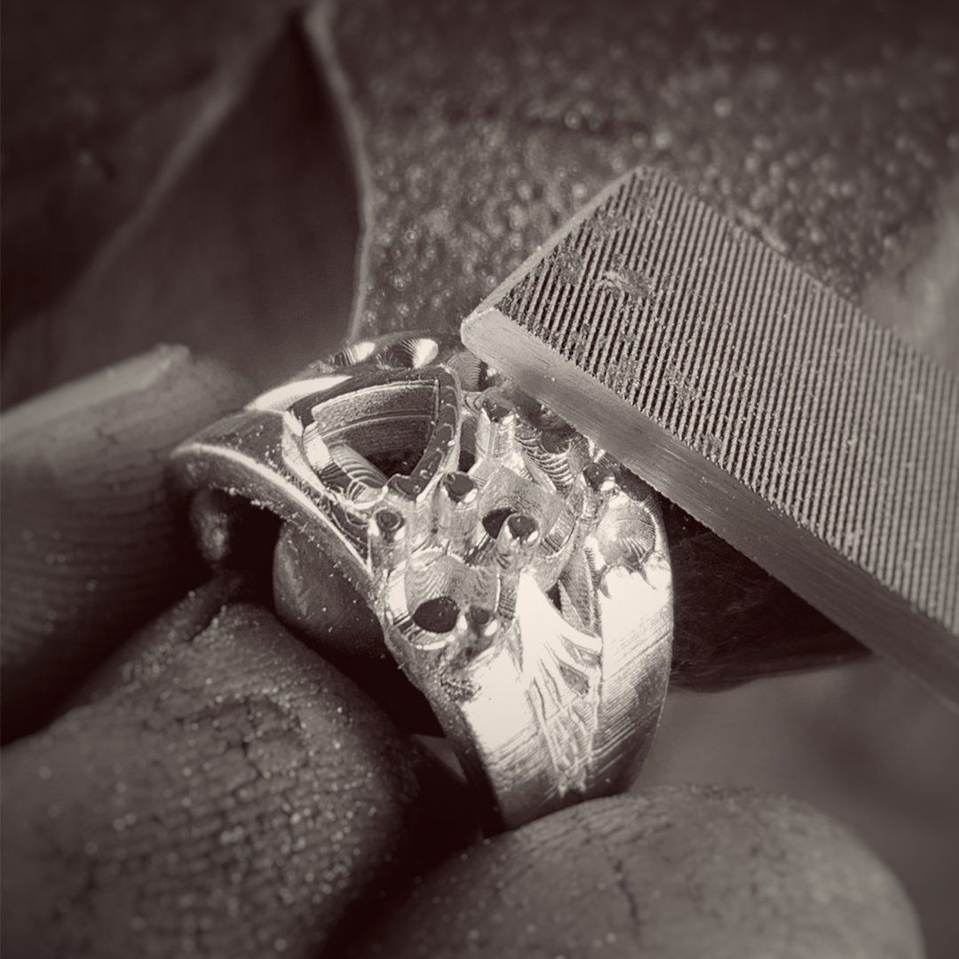 A person is filing a silver ring with a file.
