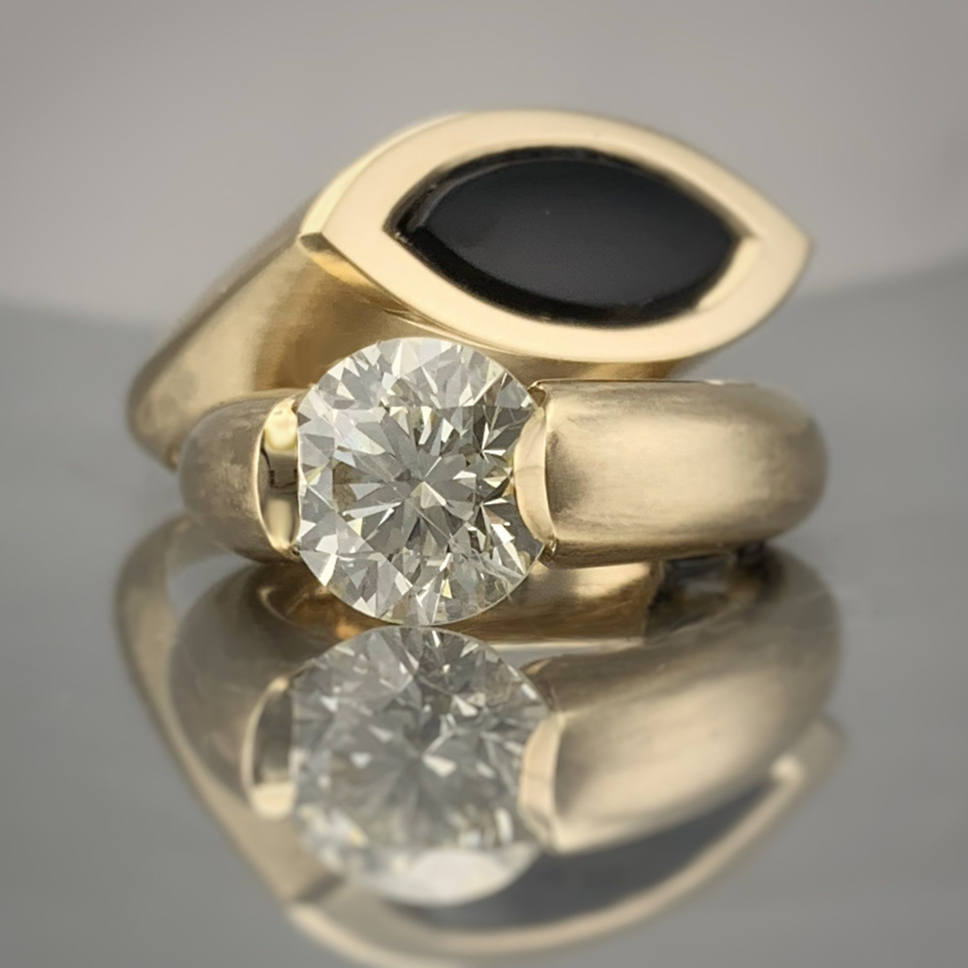A gold ring with a diamond and a black stone