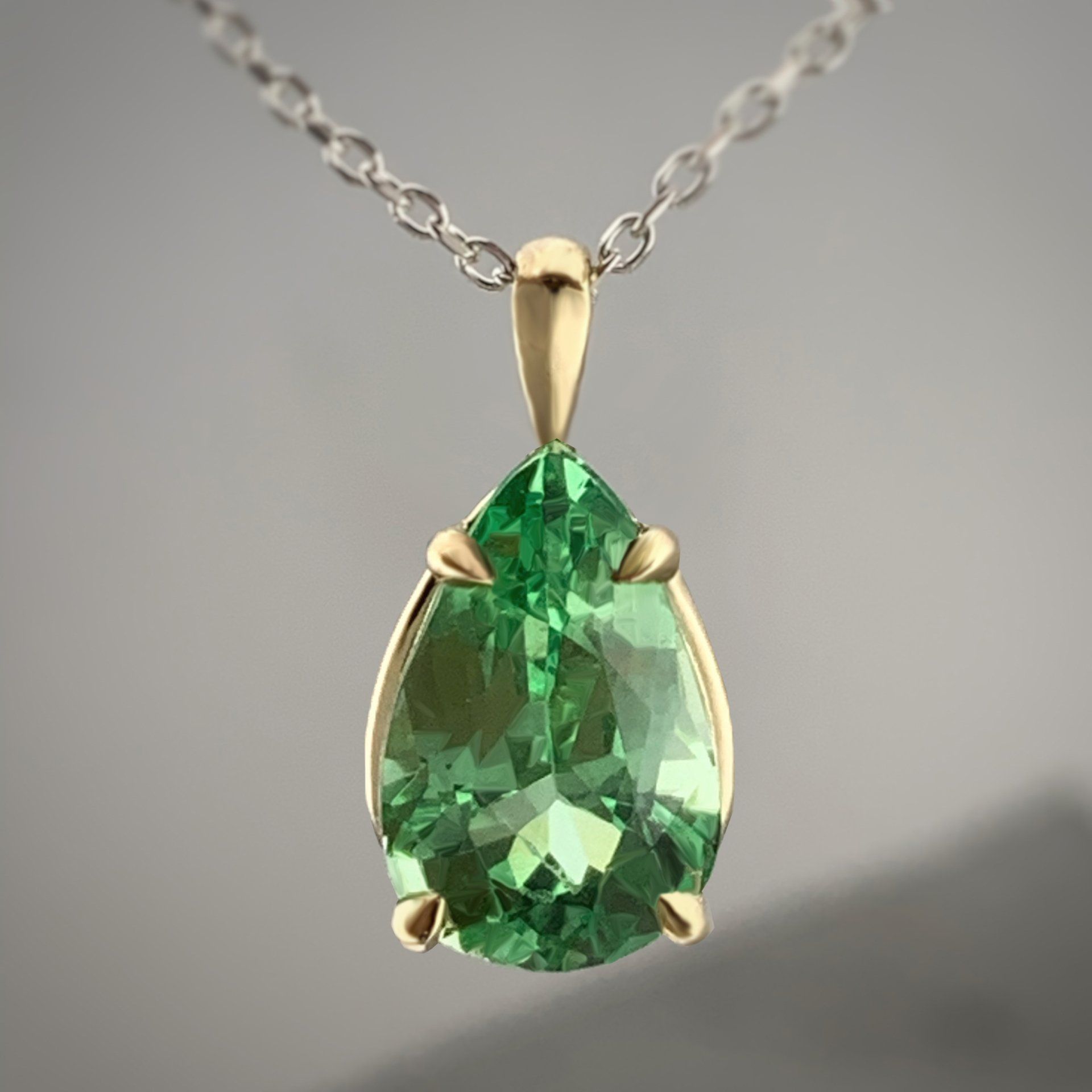 A necklace with a pear shaped emerald pendant on a chain