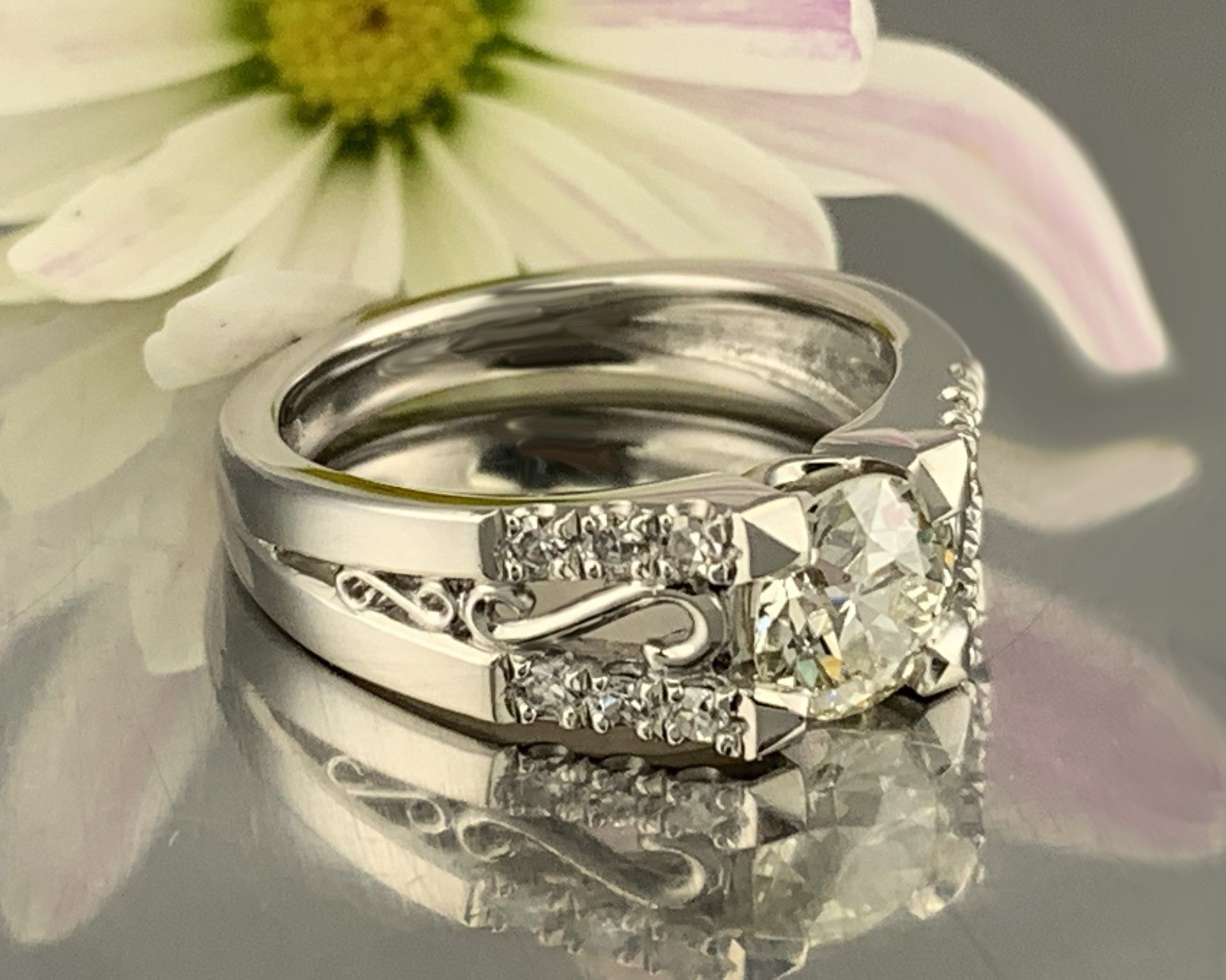 A diamond ring with a flower in the background
