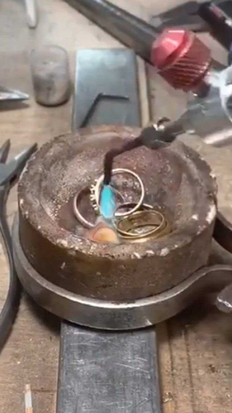 A bunch of rings are being soldered in a bowl on a table.