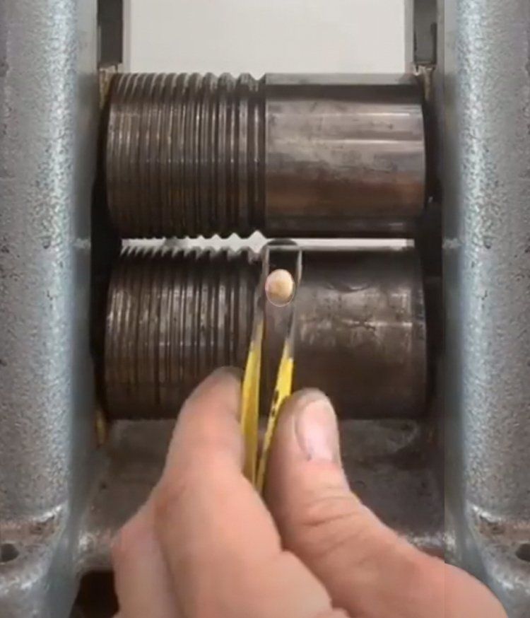 A person is holding a pair of tweezers in front of a machine.