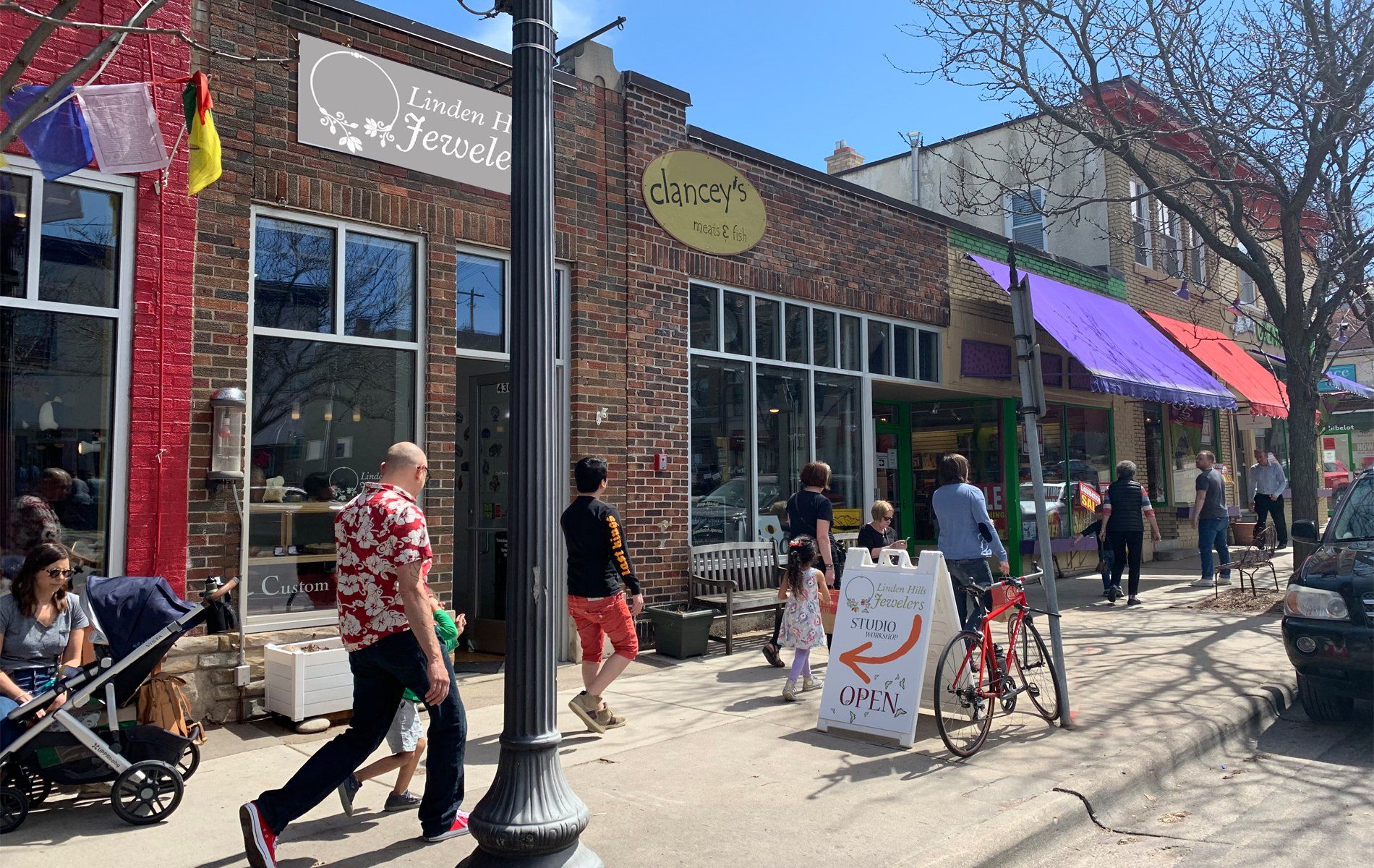 A group of people are walking down a sidewalk in front of a store.