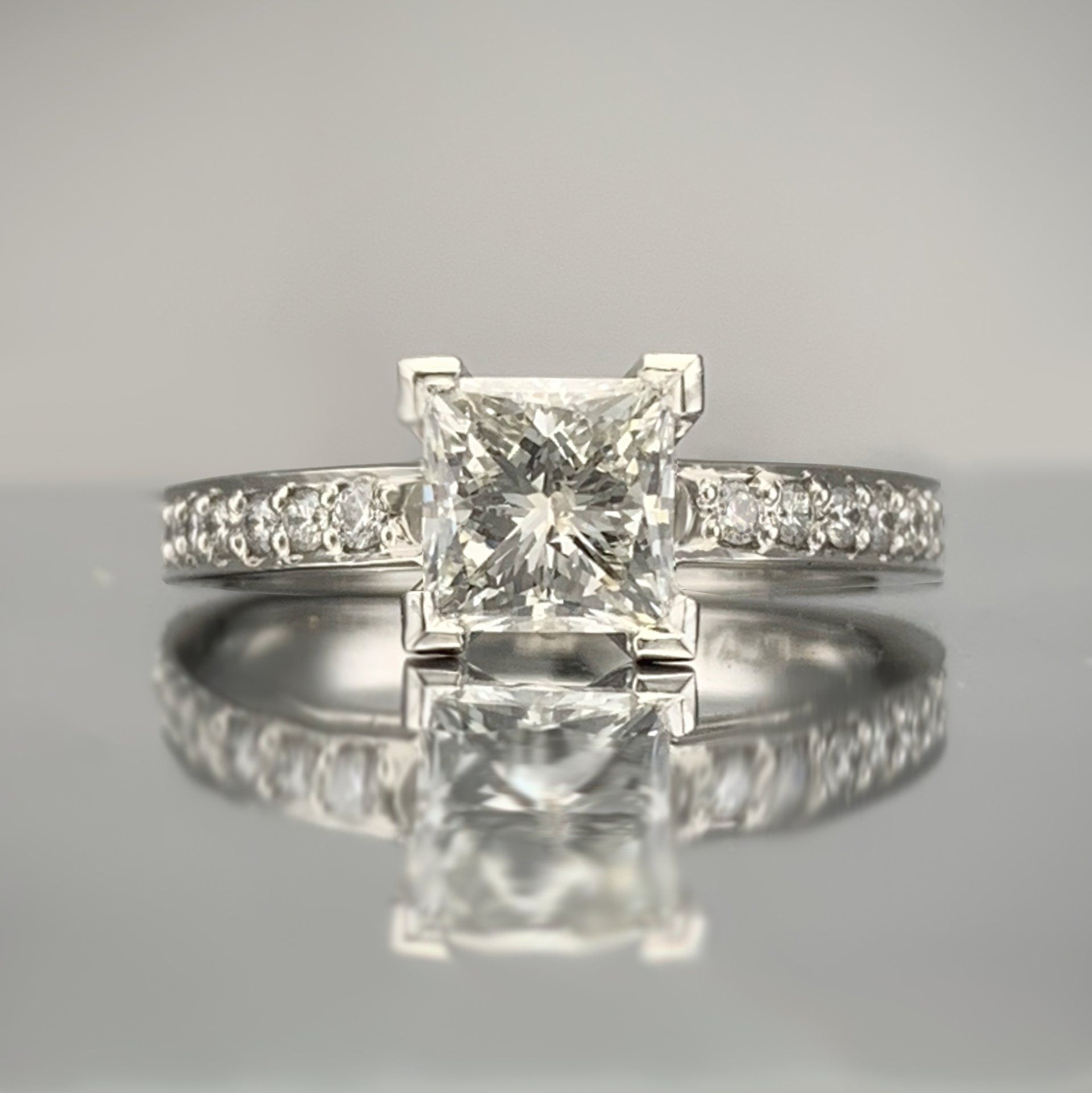 A diamond ring with a square diamond in the center is sitting on a table.