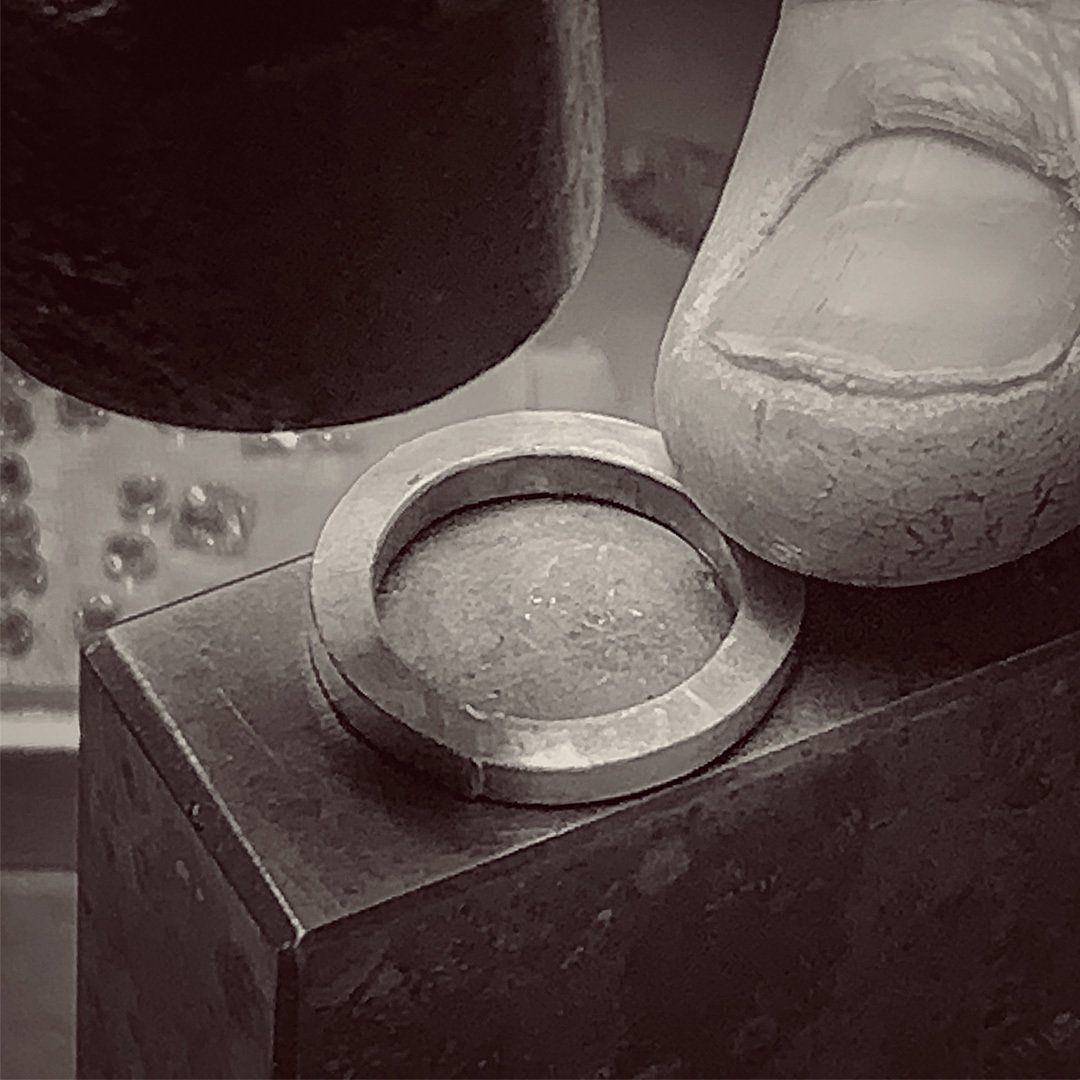 A person is hammering a metal ring with a hammer.