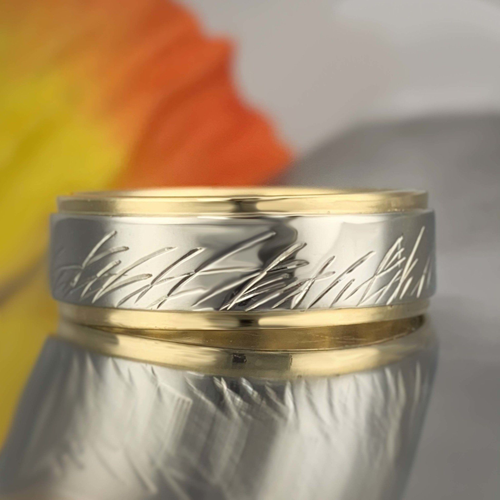 A silver and gold ring with feathers engraved on it