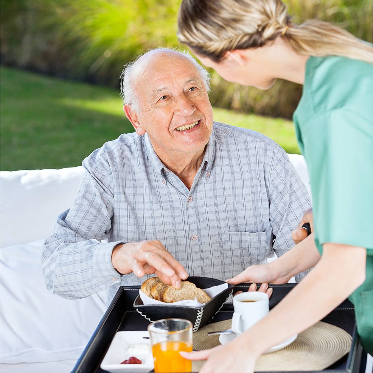 A woman is serving an elderly man a tray of food