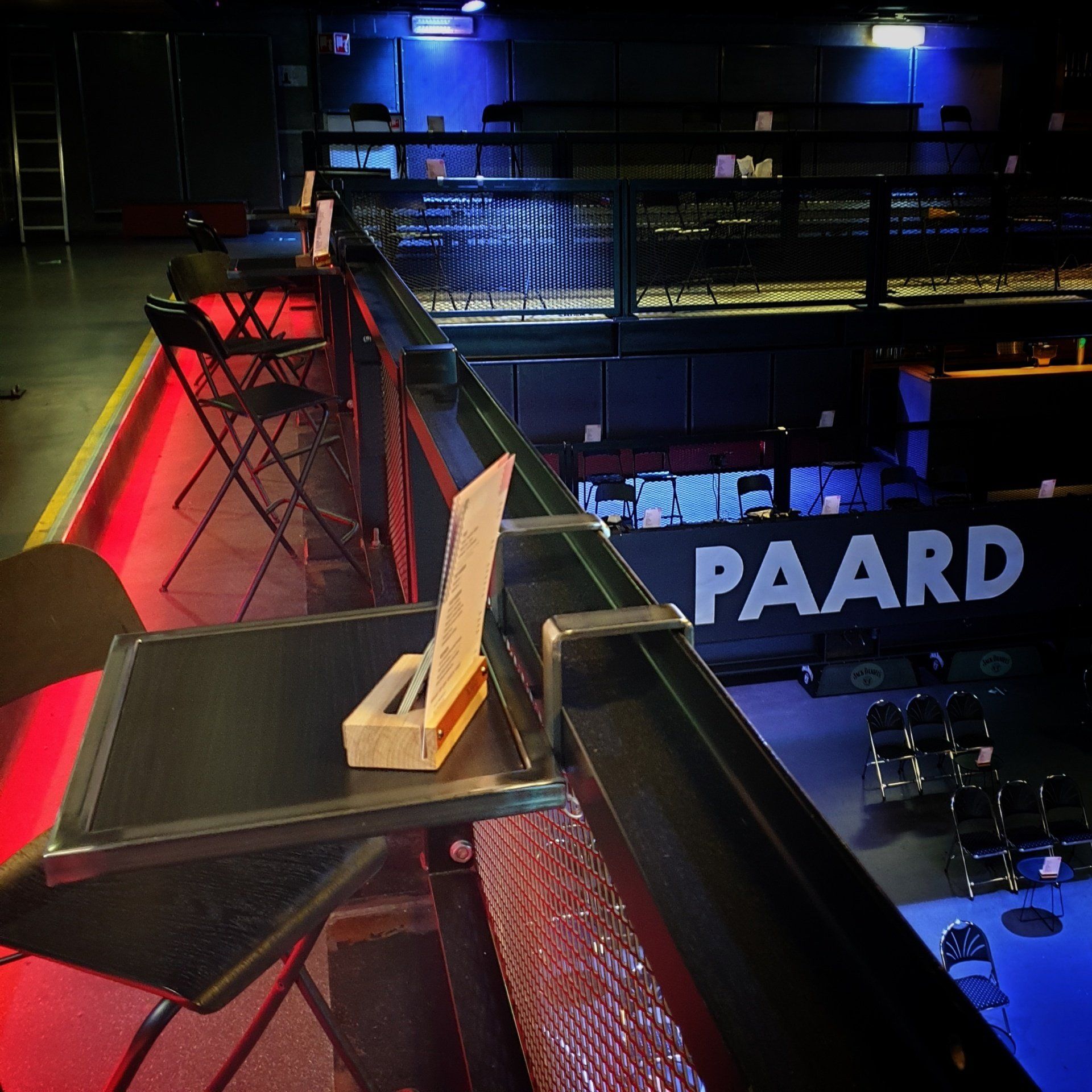 Uitzicht vanaf een balkonreling op een lege concertzaal met het bord 