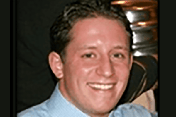 a man in a blue shirt is smiling for the camera .