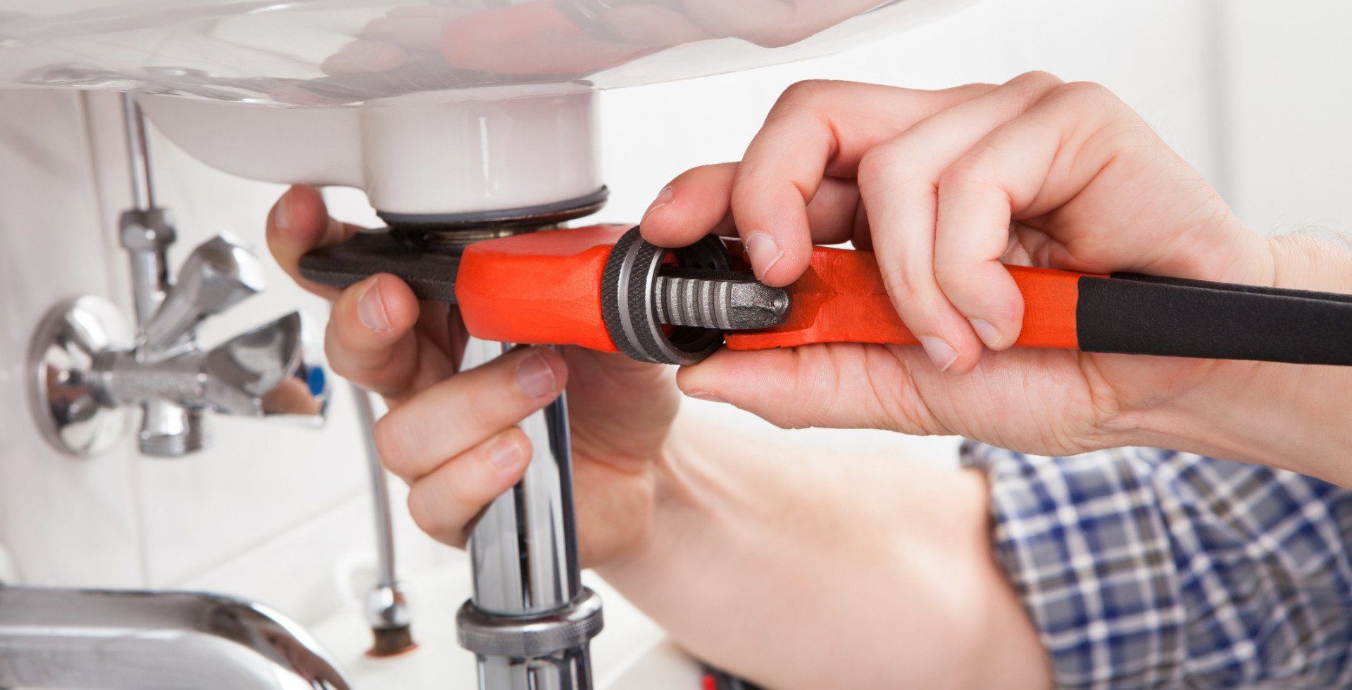 Plumber Using A Wrench To Fix A Sink Pipe
