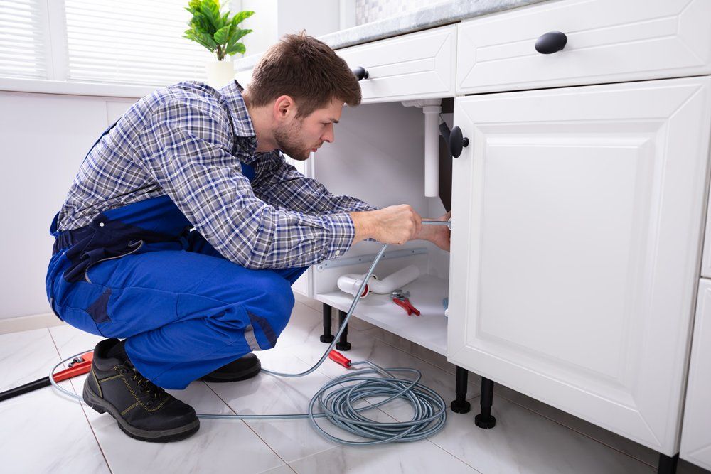 Plumbing Service in a House — Evansville, IN — Gary's Plumbing Service Inc A man performing a residential water heater system repair in Evansville, IN
