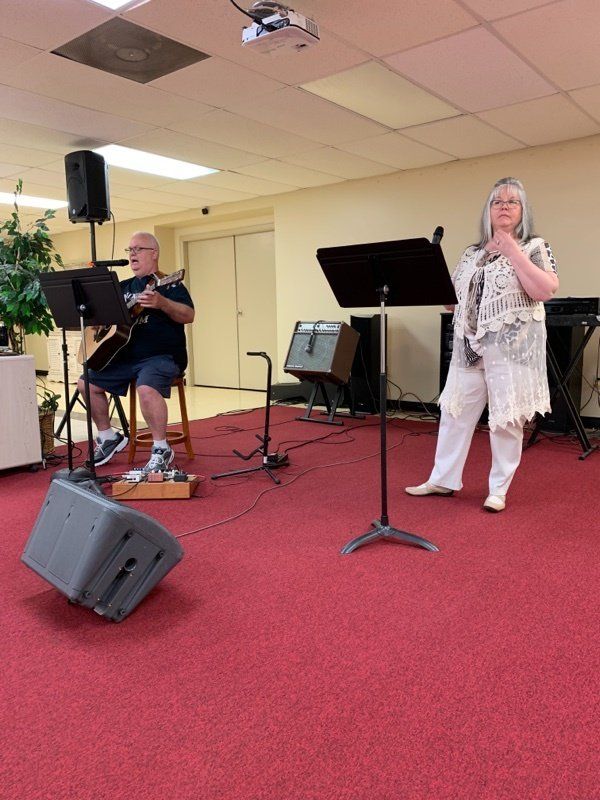 A man playing a guitar and a woman singing on a stage