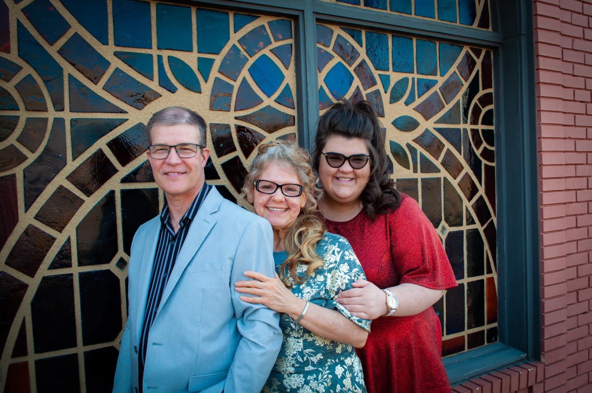 A family is posing for a picture in front of a stained glass window.