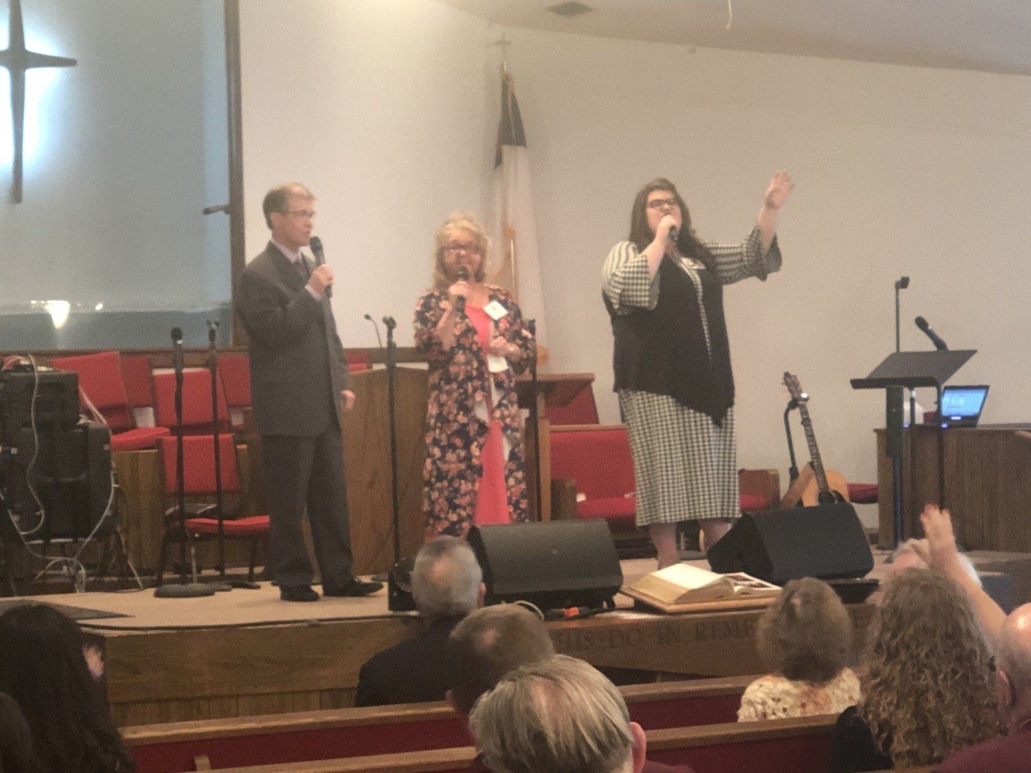 A man and two women singing in front of a crowd in a church