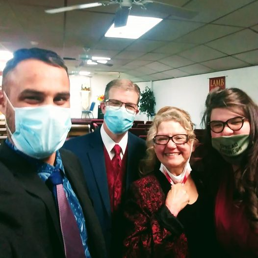 A group of people wearing face masks are posing for a picture