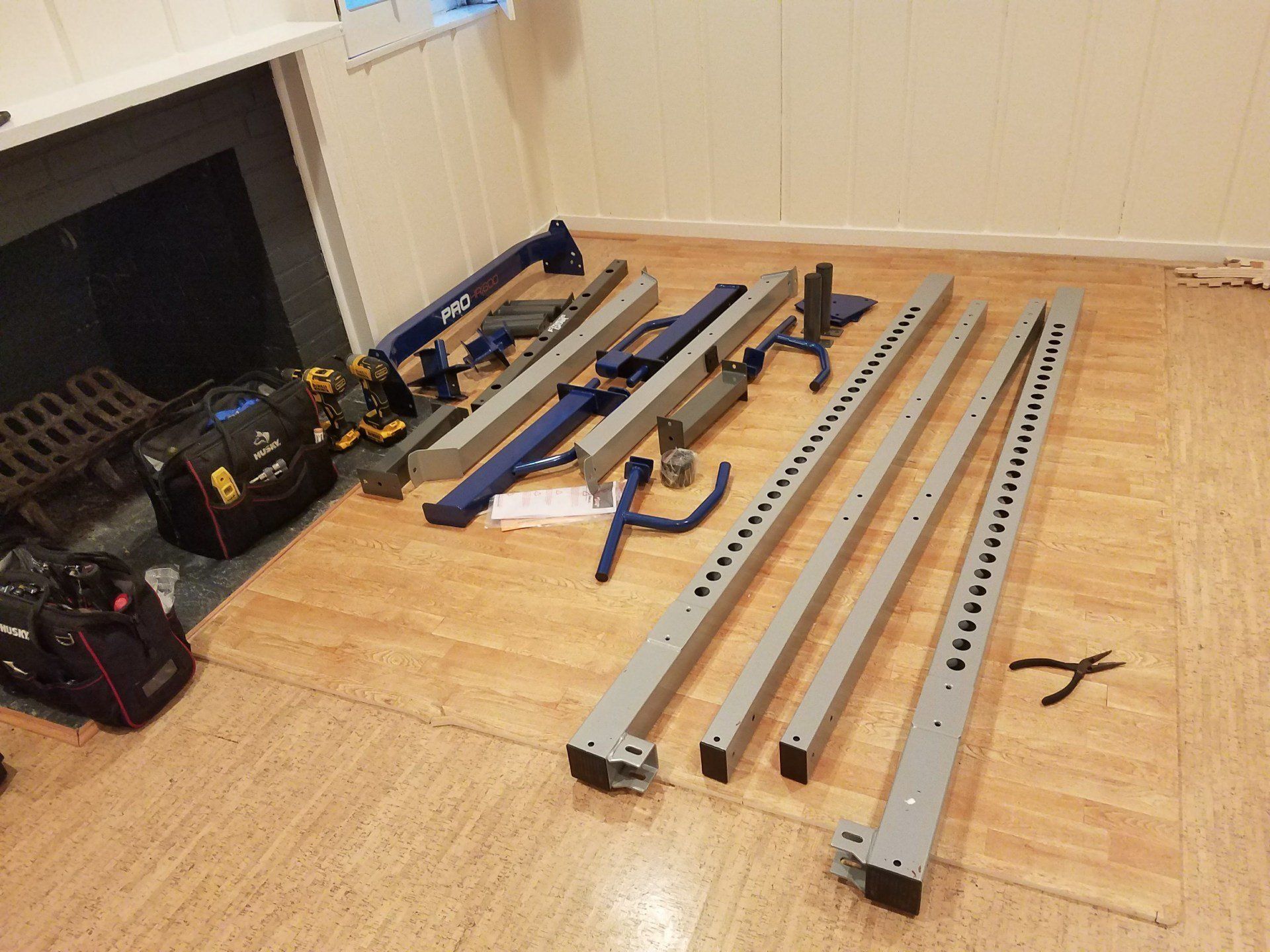 A bunch of pieces of metal parts are laying on the floor in a living room.