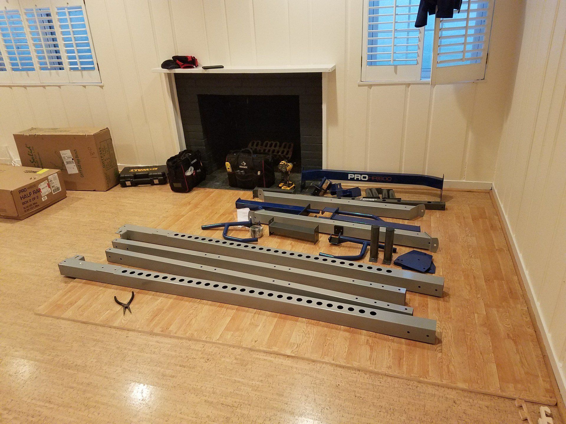 A room with a fireplace and a bunch of gym parts  on the floor