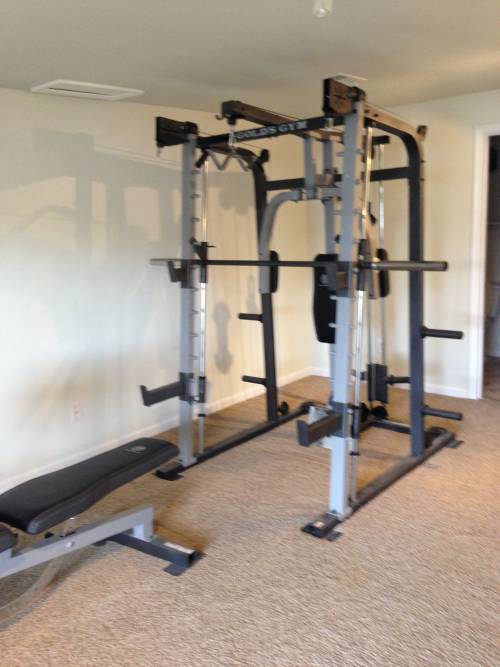 A Gold's gym with a bench and a squat rack