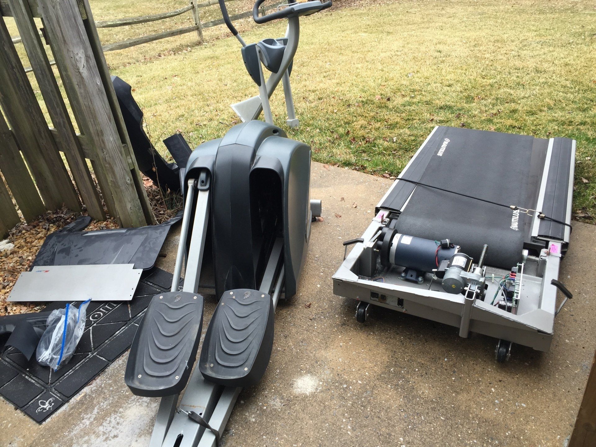 A treadmill and an elliptical are sitting on a sidewalk.