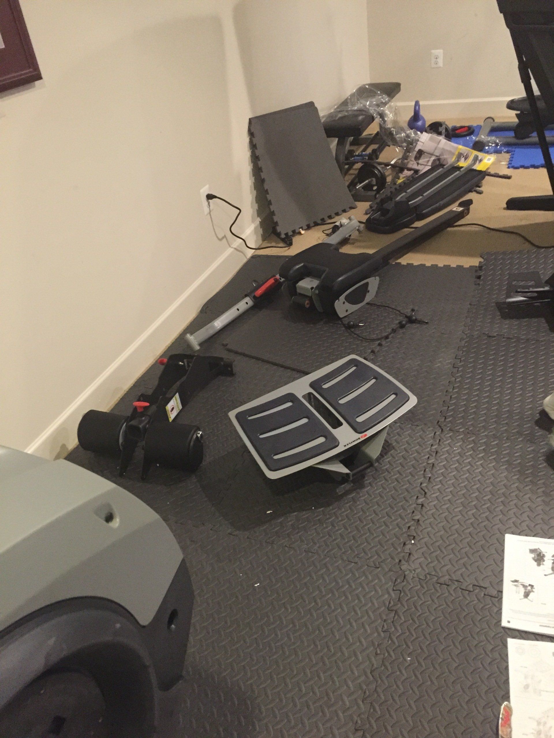 A room with a lot of exercise equipment parts on the floor
