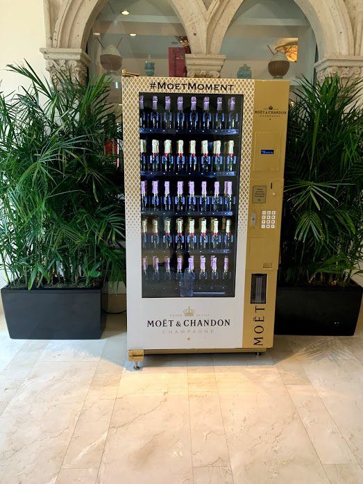 A moet & chandon vending machine is surrounded by plants