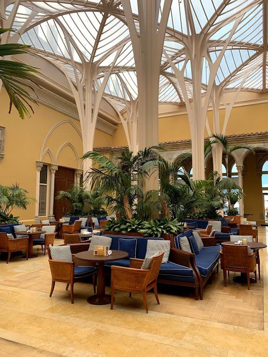 A large room with tables and chairs and trees in the ceiling.