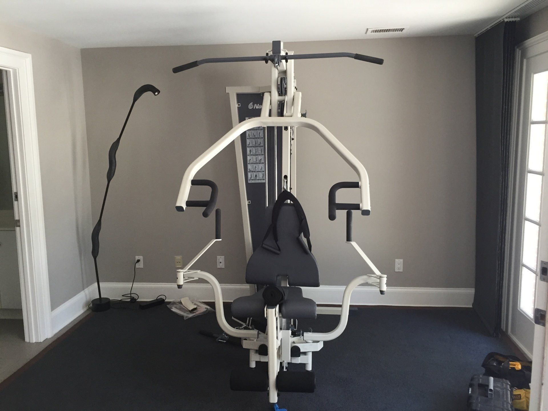A single station gym machine is sitting in a room next to a window