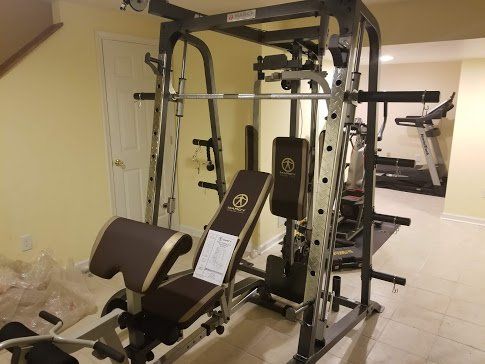 A Marcy gym with a bench and a treadmill in a basement.