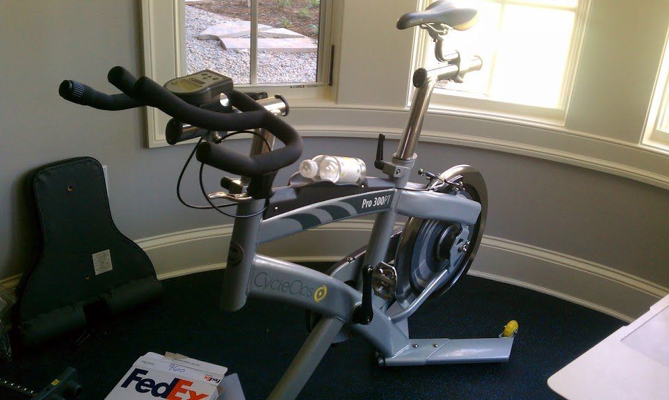 A fedex bag sits on the floor next to an exercise bike