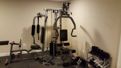 A double stuck gym filled with lots of exercise equipment and a treadmill.