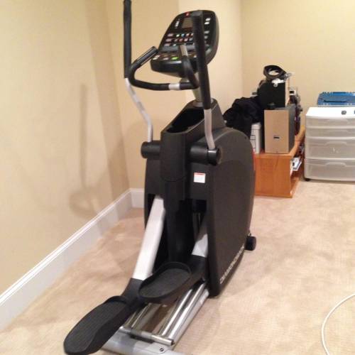 An elliptical machine is sitting in a corner of a room