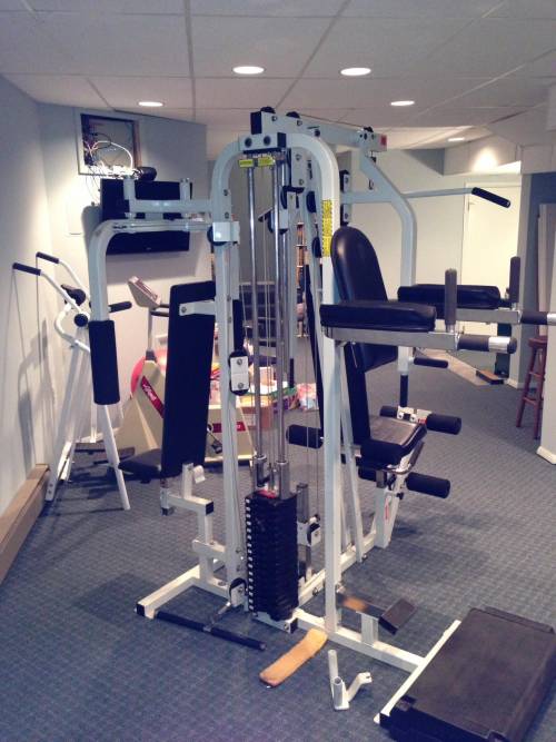 A gym filled with lots of equipment including a machine that does a pull up