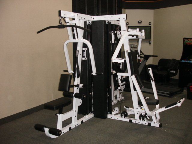 A multi station gym with a treadmill and an arcade machine