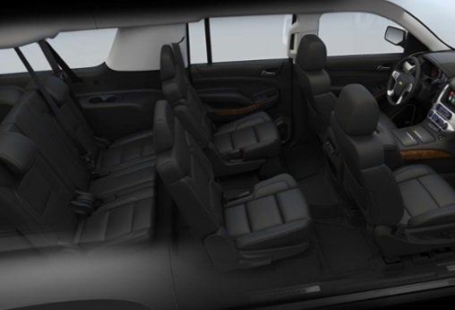Interior view of a black SUV with multiple rows of leather seats, dashboard, and steering wheel.