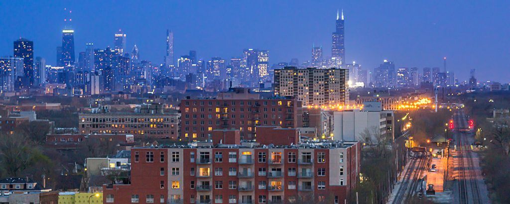 An aerial view of a city skyline at night with a brick building in the foreground.