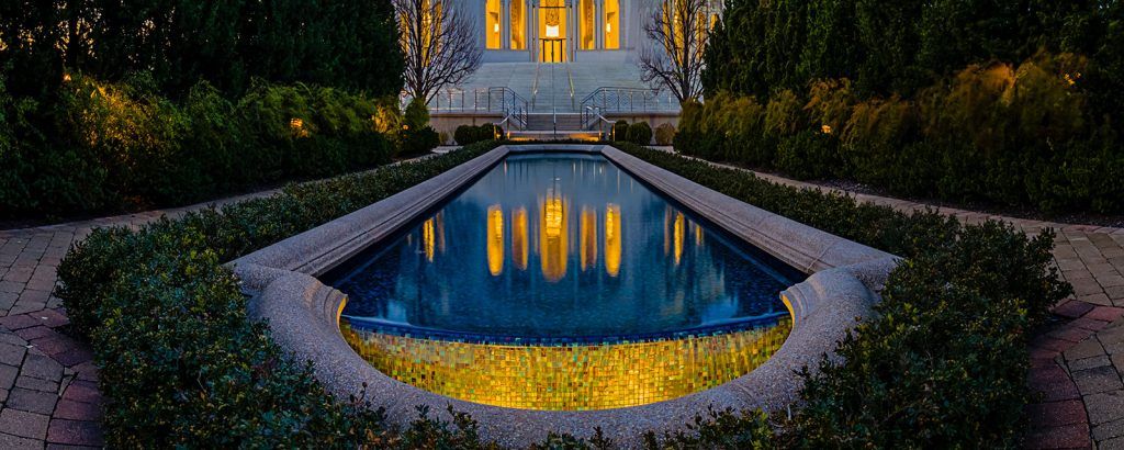 A large swimming pool with a house in the background at night.