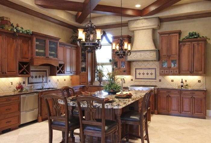 Stunning traditional kitchen remodel with warm stained raised panel cabinetry, wood ceiling beams, and tile backsplash.