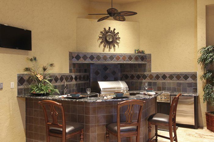 Raised bar seating area overlooking built in grill in an outdoor kitchen remodel.