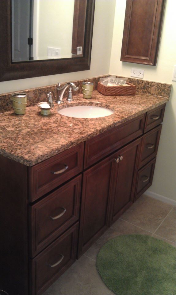 Granite countertops on dark stained vanity cabinets with mitered doors and matching medicine cabinet.