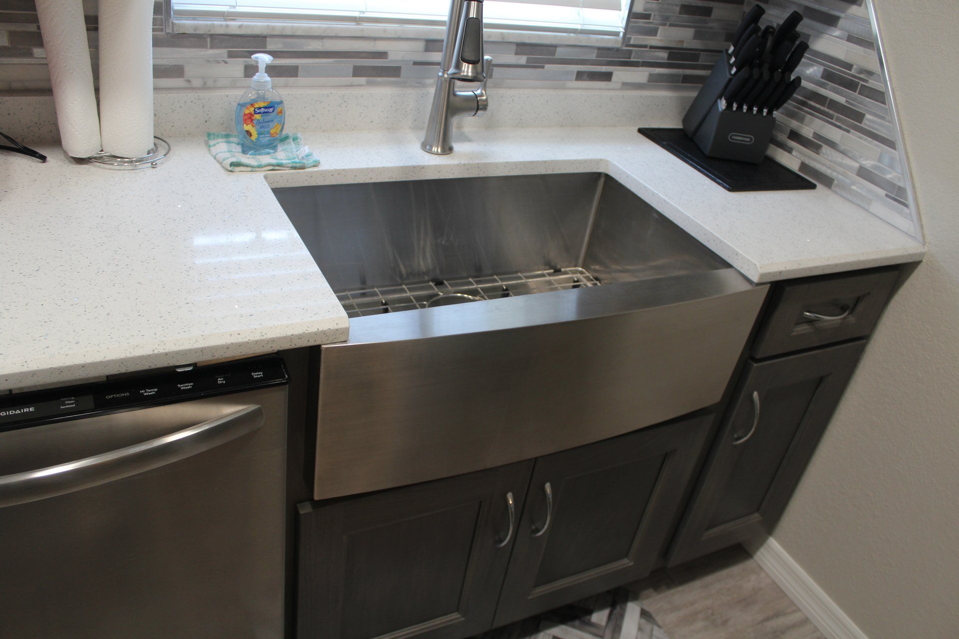 Stainless steel farmhouse sink in shaker cabinetry kitchen remodel. White quartz countertops.