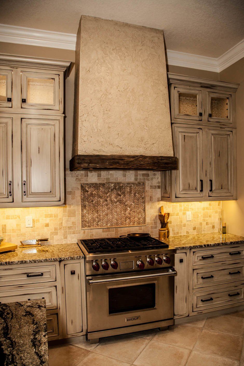 Rustic kitchen remodel with weathered raised panel cabinetry and large unique decorative wood ventilation hood.
